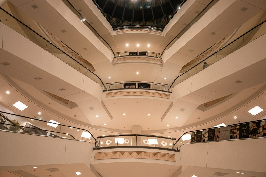 Shopping centre atrium with escalators and storefronts